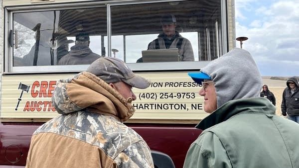 Män som deltar i en lantbruksauktion vid en mobil auktionsvagn.